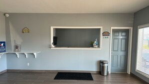 Zona de recepción con un mostrador blanco, un tapete negro, un cubo de basura y una puerta con la leyenda 'Solo personal'.