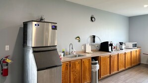 Una cocina moderna con electrodomésticos de acero inoxidable, armarios de madera, microondas integrado y un reloj de pared.
