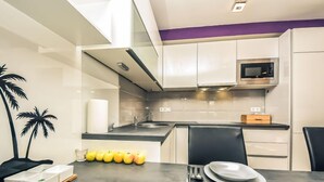 A modern kitchen with white cabinets, a microwave, and a sink. There are two chairs and a dining table with a plate and utensils on it. - Apartment Mare by Interhome (Zadar)