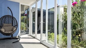 A modern interior with a hanging chair, large glass doors leading to a garden, and a blue wall. - Apartment Mare by Interhome (Zadar)