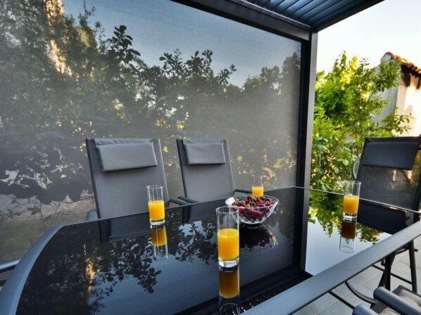 Ein Glastisch mit zwei Stühlen, einer Obstschale und zwei Gläsern Orangensaft.