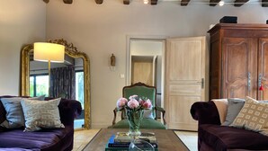 A living room with two dark purple sofas, a green armchair, and a coffee table with books and a vase of flowers. - Stylish farmhouse with pool, sleeps 8-10 (Verneuil-sur-Indre)