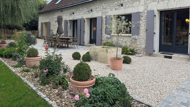 A stone house with a tiled roof, outdoor seating, and a garden with potted plants. - Stylish farmhouse with pool, sleeps 8-10 (Verneuil-sur-Indre)