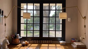 A kitchen with a large window, two wall-mounted lamps, a horse sculpture, a pot with utensils, and jars on the windowsill. - Stylish farmhouse with pool, sleeps 8-10 (Verneuil-sur-Indre)