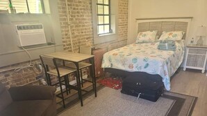Un dormitorio con una cama, un escritorio, una silla, una maleta y una mesita de noche.