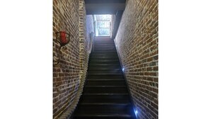 Una estrecha escalera de ladrillo con una claraboya en la parte superior.