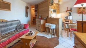 A cozy living room with a sofa, a coffee table, and a red lamp. - Bel Alp 23 by Interhome (Saint Gervais)
