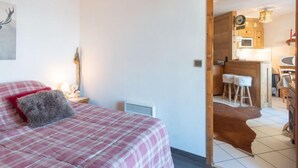A bedroom with a bed, a nightstand, a lamp, and a wall-mounted clock. - Bel Alp 23 by Interhome (Saint Gervais)