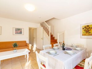 Un coin repas avec une table dressée pour quatre personnes, un escalier et un canapé.