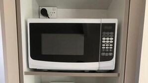 Een keuken met een magnetron, broodrooster, waterkoker en planken met servies en lekkernijen.