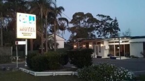Een motel met een bord, omringd door groen en bomen.