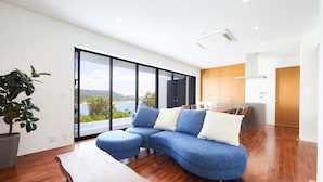 A modern living room with a large sectional sofa, a wooden coffee table, and a potted plant. - E-horizon Resort Premium sesokoD (Motobu)