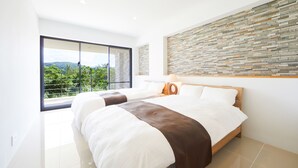 A modern bedroom with a large bed, a view of greenery through a sliding door, and a textured wall. - E-horizon Resort Premium sesokoD (Motobu)
