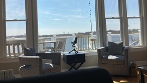 Ein Zimmer mit großen Fenstern und Blick auf ein Gewässer, ausgestattet mit zwei Sesseln und einem kleinen Tisch.