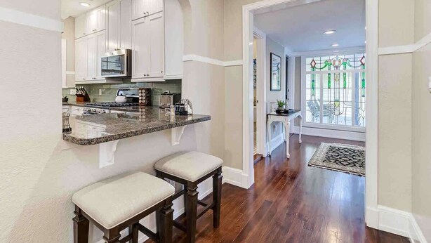 A modern kitchen with white cabinets, a granite countertop, and two bar stools. - Sleeps 19 Guests ~ Prime Location Near Lake & FSC (Lakeland)