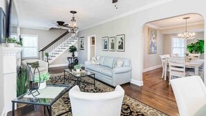 A spacious living room with a staircase, a dining area, and a chandelier. - Sleeps 19 Guests ~ Prime Location Near Lake & FSC (Lakeland)