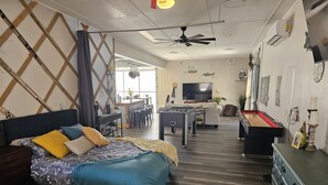 Una habitación moderna y bien iluminada con cama, sofá, escritorio y una mesa de futbolín.