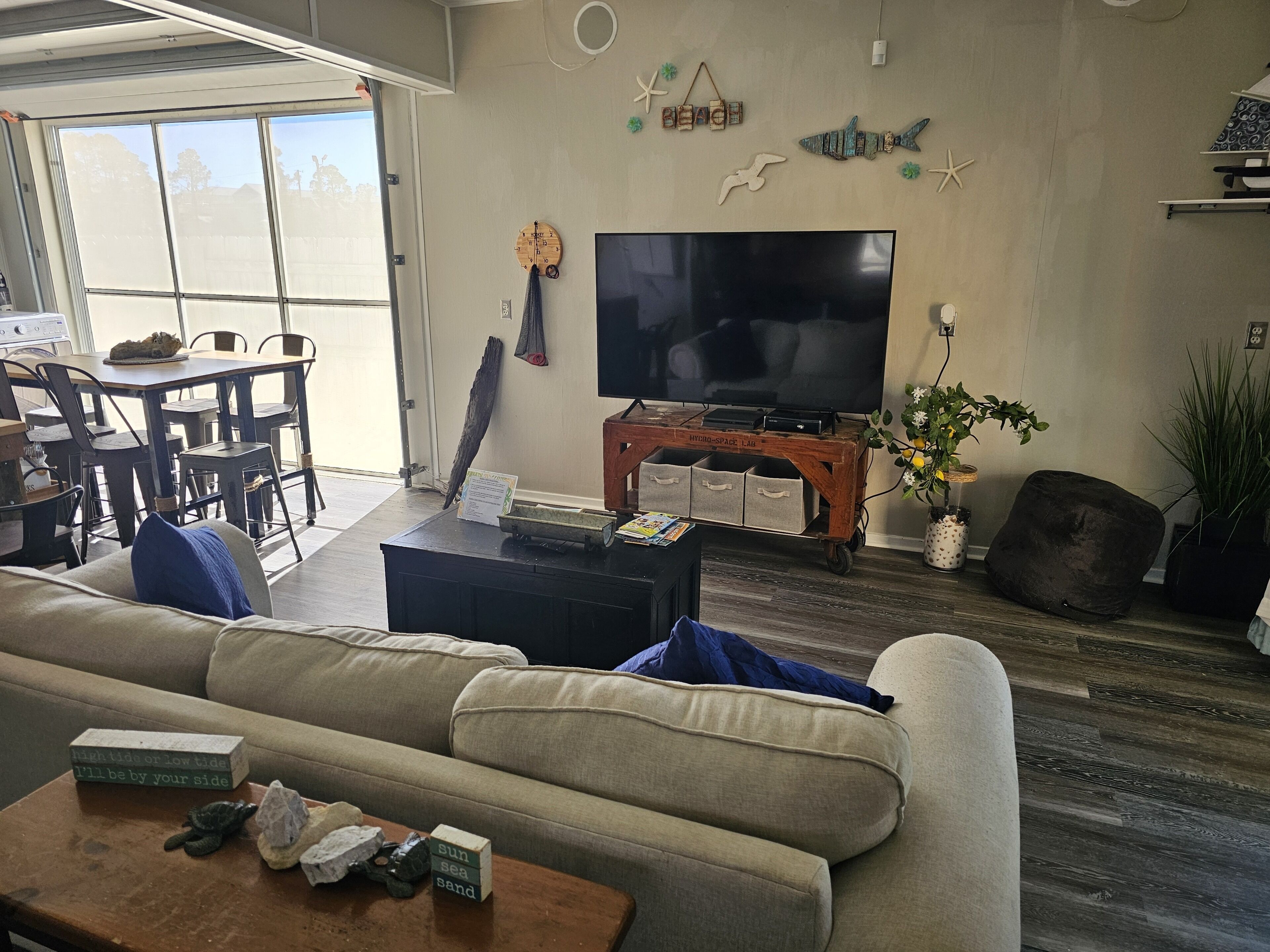 Ein Wohnzimmer mit einem großen Flachbildfernseher, einem Holztisch, einer Couch und einem Essbereich mit Stühlen.