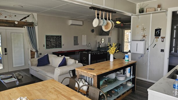 Una cocina moderna con una isla de madera, estufa integrada y un rincón comedor con sofá y sillas.