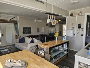 A modern kitchen with a wooden island, a built-in stove, and a dining area with a sofa and chairs. - Hidden Gem Guest House, 15min Pier Park, 5 min Beach & Publix Sports Complex (Panama City Beach)