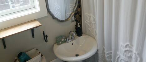 Une salle de bain avec un lavabo blanc, un miroir, des toilettes et un rideau de douche.