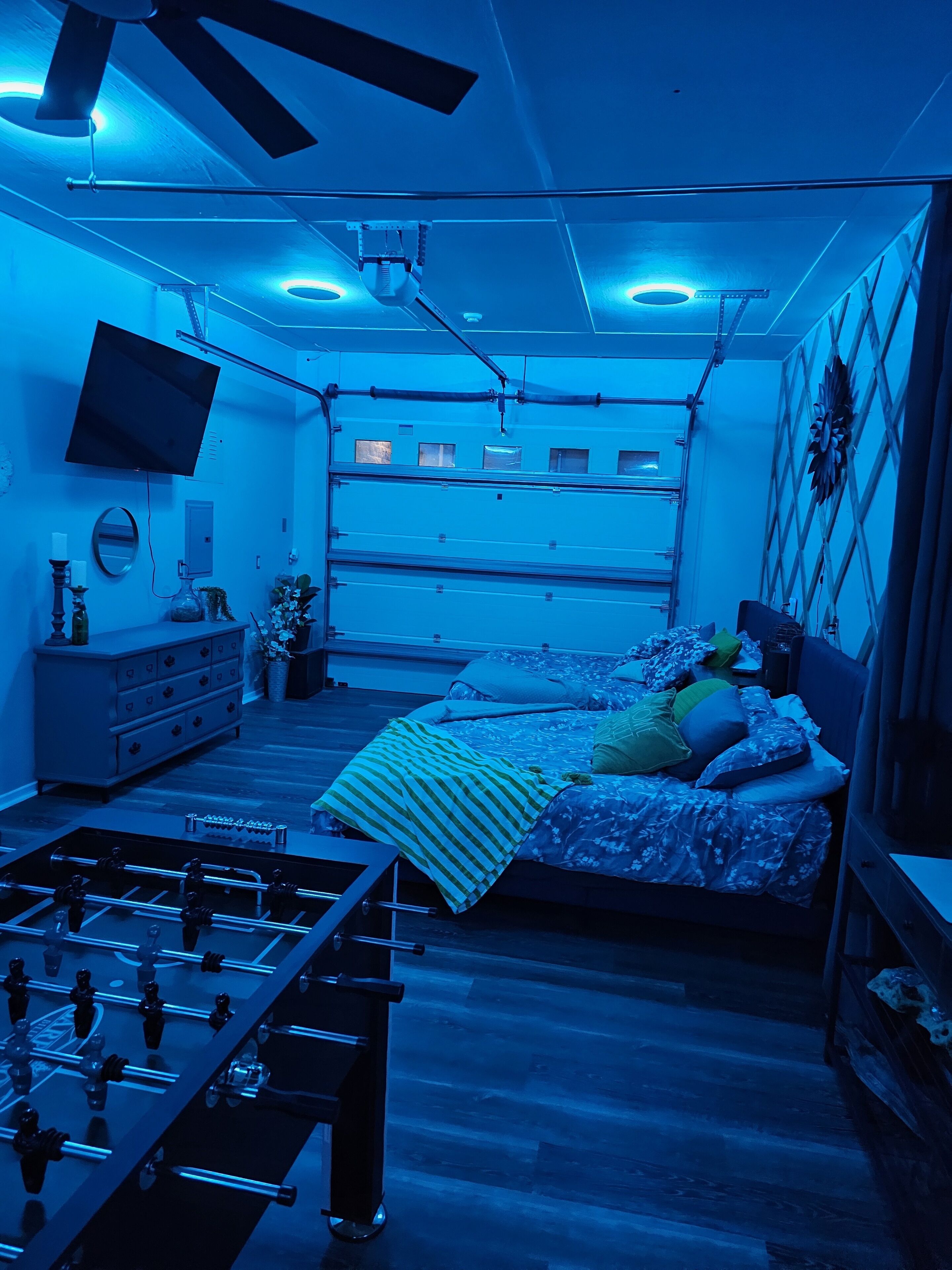 Quarto com uma cama, televisão, ventoinha de teto e janela.