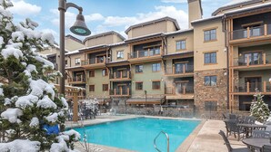 A multi-story hotel with a swimming pool, balconies, and a snow-covered landscape. - Lodge-style First-Class Resort. Gondola outside-SOOOO Convenient! Sleeps 4 (Park City)