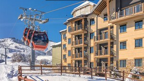 A multi-story hotel with balconies, a ski lift, and a snowy mountain backdrop. - Lodge-style First-Class Resort. Gondola outside-SOOOO Convenient! Sleeps 4 (Park City)