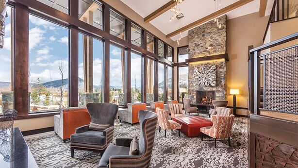 A spacious lounge with large windows, comfortable seating, a fireplace, and a stone accent wall. - Lodge-style First-Class Resort. Gondola outside-SOOOO Convenient! Sleeps 4 (Park City)