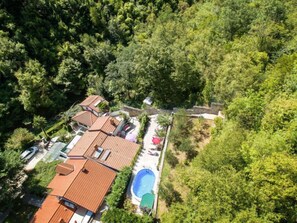 An aerial view of a residential area with multiple houses, a swimming pool, and lush greenery.