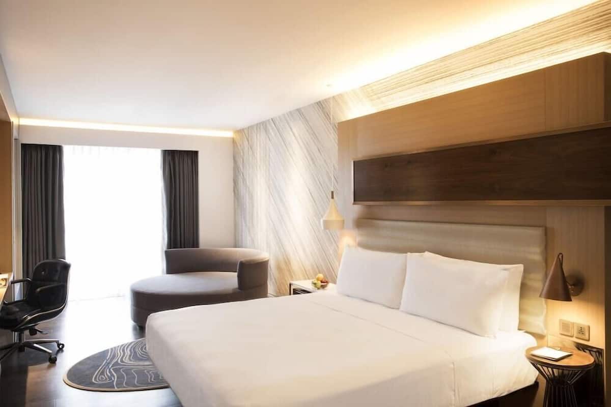 Une chambre d’hôtel moderne avec un grand lit, un bureau, une chaise et une petite table.