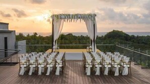 An outdoor wedding setup with a wooden deck, white chairs, and a canopy. - Le Méridien Goa, Calangute (Calangute)