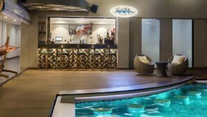 A pool area with a bar, lounge chairs, and a reception desk. - Le Méridien Goa, Calangute (Calangute)