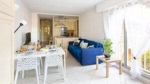 A modern apartment with a dining area, a blue sofa, and a kitchen in the background.