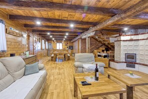 A cozy interior with a wooden ceiling, a dining area, a sofa, and a fireplace.