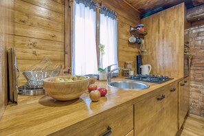 A wooden kitchen with a large wooden bowl of apples, a sink, and a stove.