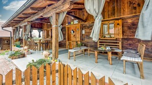 Une cabane en bois rustique dotée d’un patio couvert, de meubles en bois et d’un espace jardin.