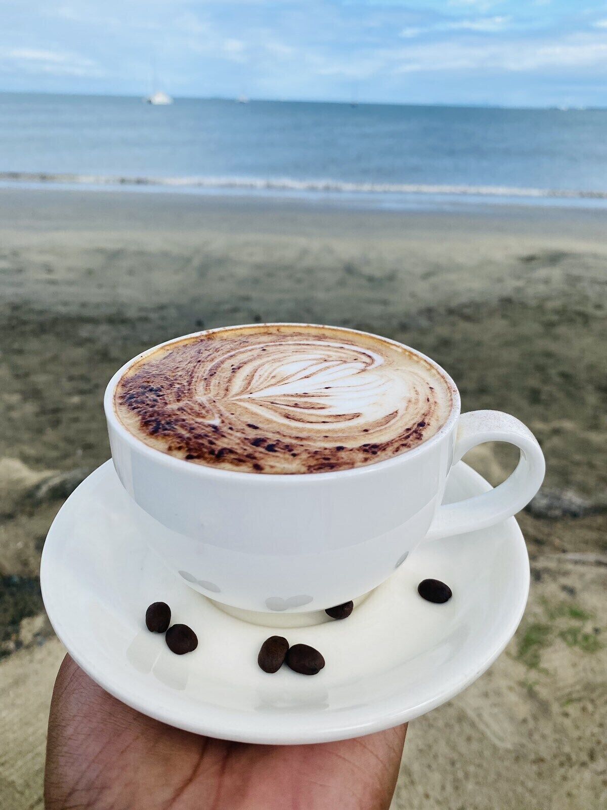 Una taza de café con arte de latte en la playa.