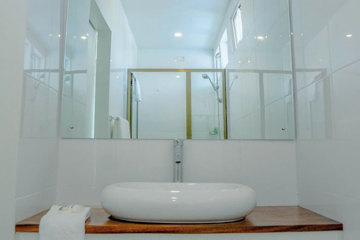 A modern bathroom with a large mirror, a white sink, and a wooden countertop.