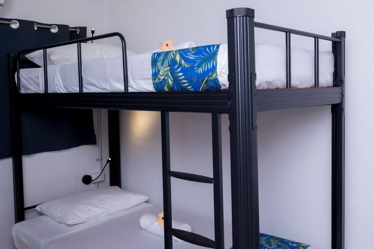 A bunk bed with white bedding and a blue tropical print on the lower bunk.