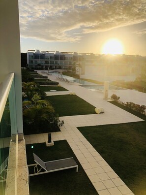 A modern hotel with a pool, lounge chairs, and a view of the sunset. - Canarock condos apartment complete  (Punta Cana)