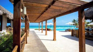 A wooden covered walkway leading to a beach with lounge chairs and umbrellas.