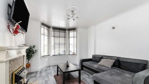 A modern living room with a grey sofa, a black coffee table, and a fireplace. - House - Sleeps 10 - Garden - Close to City Centre (Colchester)