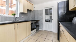 A modern kitchen with light wood cabinets, a black countertop, and a black refrigerator. - House - Sleeps 10 - Garden - Close to City Centre (Colchester)