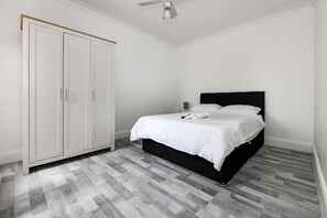 A bedroom with a bed, white wardrobe, and a ceiling fan. - House - Sleeps 10 - Garden - Close to City Centre (Colchester)