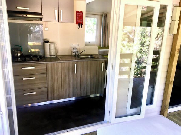 Una kitchenette compacta con estufa a gas, cafetera y lavamanos.