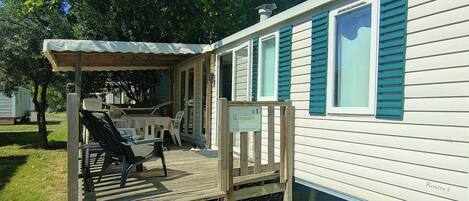 A mobile home with a porch, outdoor seating, and a sign indicating it is a Greenbriar property.