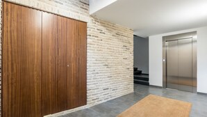 Un interior modern amb un armari de fusta, una paret de maó, un paviment de rajoles grises i una catifa marró.