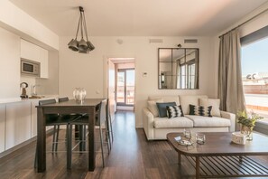 A modern living room with a sofa, coffee table, and dining area. - Sierpes Luxury Penthouse Private Terrace (Sevilla)