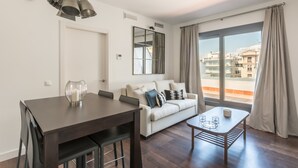 Un saló modern amb zona de menjador, sofà i una finestra gran amb cortines.